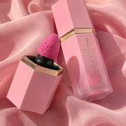 Pink lip gloss with applicator on a pink fabric background