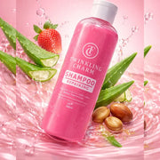 Pink shampoo bottle with aloe vera leaves and strawberries on a pink background