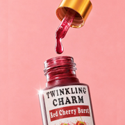 Red cherry burst nail polish with dropper on a pink background