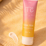 Tube of sunscreen with pink and yellow gradient on a sandy background