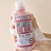 Hand holding a bottle of Twinkling Charm Clean On Me Hydrating Body Wash with bubbles in the background.