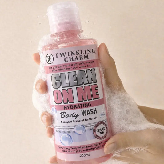 Hand holding a bottle of Twinkling Charm Clean On Me Hydrating Body Wash with bubbles in the background.